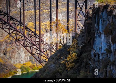 Die Kragarmbrücke aus Metall über den Snake River Canyon mit farbenfrohen Bäumen, die im Herbst auf den Felsen wachsen, Twin Falls, Idaho Stockfoto