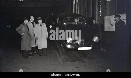 1946, historische, drei Werksleiter, die einen neuen Volkswagen Wagen von einer Rampe im Volkswagen Werk in Wolfsburg, Deutschland, abfahren sahen. Zu dieser Zeit unter der Kontrolle der britischen Armee und obwohl er durch alliierte Bombenangriffe schwer beschädigt wurde, funktionierte der riesige Industriekomplex noch und produzierte Fahrzeuge. Stockfoto