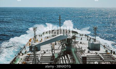 Ein riesiger Tanker segelt im Ozean. Blick von der Brücke auf Deck und Wellen, die auf das Schiff treffen Stockfoto