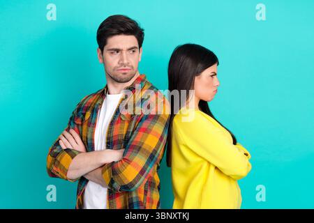 Junges Paar in Uneinigkeit, das sich mit gekreuzten Armen vor einem blaugrünen Hintergrund ausgibt, der Konflikte und Emotionen symbolisiert Stockfoto