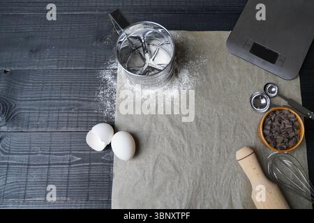 Blick von oben auf die wichtigsten Backwaren auf einem schwarzen Holztisch mit Pergamentfüllung, perfekter Vorbereitungsmoment für die Küche Stockfoto