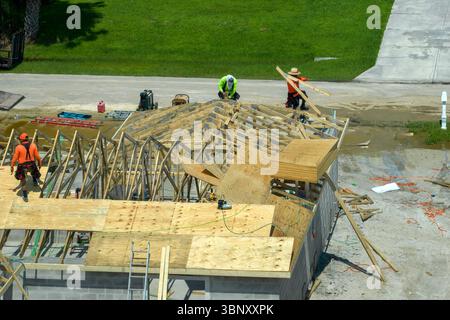 Bauarbeiter, die an der Dachkonstruktion eines unfertigen Wohnhauses mit Holzrahmenstruktur im Vorstadtgebiet von Florida arbeiten. Wohnungsbau Stockfoto