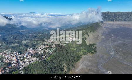 Das Dorf Cemoro Lawang liegt an der Grenze zwischen fruchtbaren Hängen und der kargen Caldera und bietet einen atemberaubenden Kontrast zwischen lebhaftem Grün und wildem Grün Stockfoto