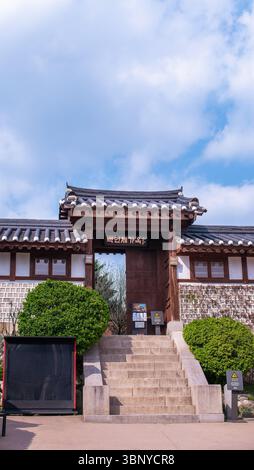 Seoul, Südkorea - 10. April 2025: Ein traditionelles koreanisches Hanok-Haus mit Steintreppen und grünen Büschen unter klarem Himmel. Dieser klassische Archi Stockfoto