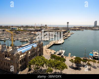 Blick aus einem hohen Winkel auf den Hafen von Port Vell in Barcelona, Spanien, mit Blick auf den Yachthafen, Moll d'Espanya und das alte Gebäude der Hafenbehörde an einem sonnigen Tag. Stockfoto