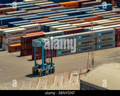 Eine Trägermaschine bewegt sich im Hafen von Barcelona in Spanien zwischen den Containern. Stockfoto