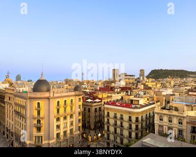 Blick über die Dächer und historischen Gebäude von Barcelona, Spanien, in der Abenddämmerung, mit Montjuic Hügel in der Ferne. Stockfoto
