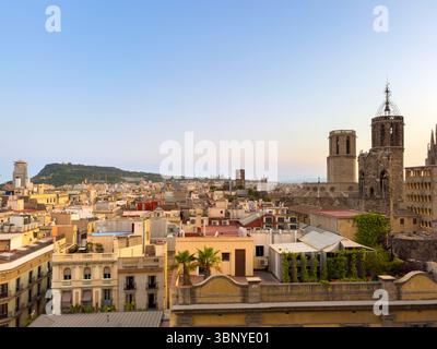 Blick über die Dächer des gotischen Viertels Barcelonas in Richtung Montjuic Hügel in der Abenddämmerung, mit sichtbaren Türmen der Kathedrale, Spanien. Stockfoto