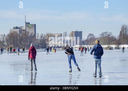 Wagenignen, Niederlande - 13. Februar 2021: Eisläufer haben Spaß in der Sonne auf gefrorenen Auen am Rhein in Holland Stockfoto