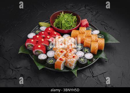 Food still-Life, Eine wunderschön gestaltete Sushi-Platte zeigt eine Vielzahl von Sushi-Brötchen, einschließlich farbenfroher Maki und Nigiri, garniert mit Algen A Stockfoto