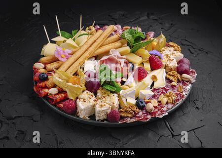 Food still-Life, Eine wunderschön gestaltete Wurstplatte bietet eine Auswahl an Käse, Wurstwaren, frischem Obst und Beilagen. Perfekt für PA Stockfoto