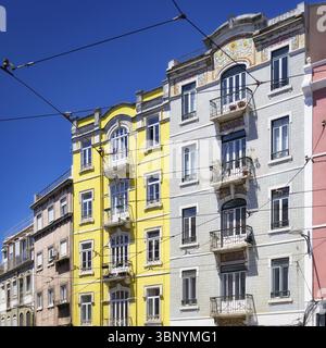 Pastellfarbene und typisch gekachelte Wohngebäude mit den allgegenwärtigen Freileitungen der historischen Straßenbahn im Stadtteil Graca in lissabon Stockfoto