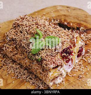 Food Stillleben, Kuchen aus gerollten Pfannkuchen mit Sahne, Kirschen und geriebener Schokolade auf Holz Stockfoto