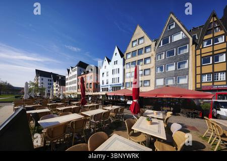 Köln, Deutschland 9. April 2025: Blick auf die bunten Giebelhäuser mit vielen Restaurants am rheinufer in köln über noch leere Tische A Stockfoto