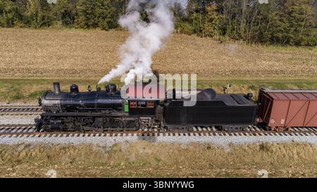 Eine Luftaufnahme eines antiken Dampffracht-Passagierzuges, der an einem Herbsttag langsam Rauch bläst Stockfoto