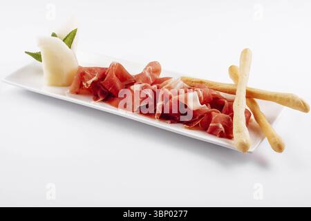 Food still-Life, Jamon Serrano, Prosciutto Crudo oder Parmaschinken und Brotstangen auf weißem Teller Stockfoto