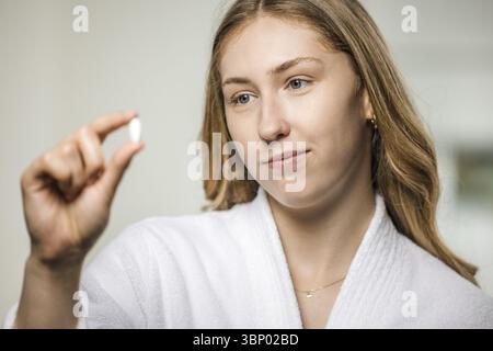 Junge, blonde Frau in einem weißen Bademantel mit Medizin Stockfoto