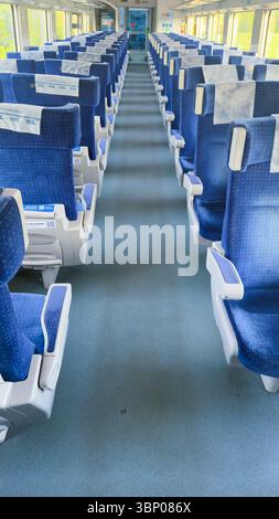 Geräumiges und komfortables Zuginnere mit blauen Sitzplätzen und sauberen Gängen für ein entspanntes Reiseerlebnis im modernen Bahnverkehr Stockfoto