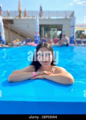 Porträt einer schönen 30-jährigen Brünetten Frau, die sich im Pool entspannt Stockfoto