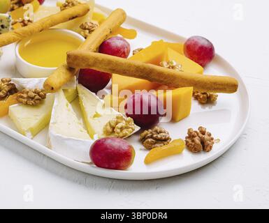 Stillleben, Käseplatte mit Honig, Nüssen und roten Trauben Stockfoto