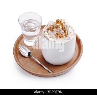 Food still-Life, Ein köstliches Dessert mit Schlagsahne und Gewürzen, in einer runden weißen Tasse auf einem Holztablett. Ein Glas Wasser und ein Löffel Stockfoto