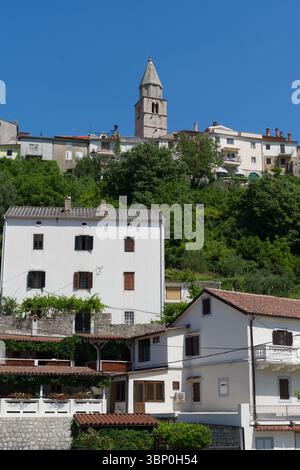 Das historische Vrbnik, Kroatien, auf einem Hügel thront, verfügt über traditionelle Häuser aus weißem Stein und einen markanten Kirchturm Stockfoto