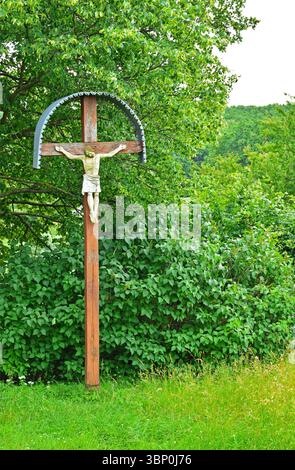 Kreuz mit Kruzifix am Rande einer Landstraße Stockfoto