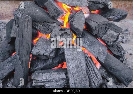 Holzkohlefeuer Hintergrund für Picknicks mit schwarzen Kohlen und lebhaften Flammen Stockfoto