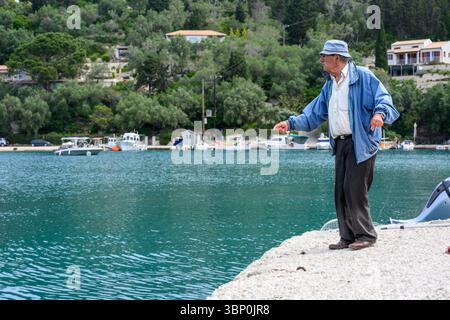 12-19/05/2025 Lakka, Paxos, Griechenland. Älterer Mann, der nur mit einer Schlange im Hafen angelt. Foto © Simon Grosset Stockfoto