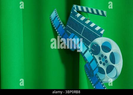 Filmklappertafel und Filmrolle hängen vor grünem Hintergrund Stockfoto