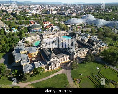 Luftaufnahme am Vormittag des Széchenyi Thermalbades in voller Sicht, mit dem Hauptzirkus von Budapest und einem Teil des Zoos von Biodóm im Hintergrund Stockfoto