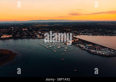 Blick aus der Vogelperspektive auf die Marina von Malahide mit angedockten Segelbooten bei Sonnenuntergang in der goldenen Stunde und warmem orangefarbenem Himmel Stockfoto