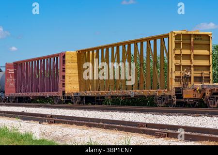 Zwei lange Wagen mit Mittelbalken sitzen an einem sonnigen Sommernachmittag in Texas im Leerlauf auf einem Bahngleis. Stockfoto