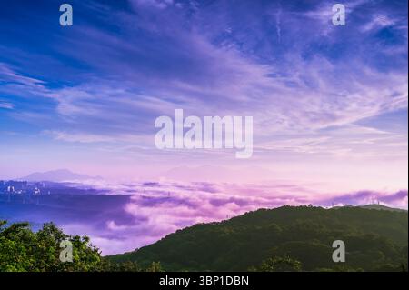 Beschreibung: Ein ruhiger Morgen entfaltet sich über den Bergen des Shulin District New Taipei City Taiwan, mit einem sanften rosa und lila Himmel über einer Decke aus Stockfoto