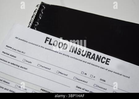 Konzept der Hochwasserversicherung Schreiben auf Formular isoliert auf Holztisch. Stockfoto