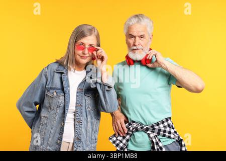 Älteres Paar in stylischen Outfits auf orangem Hintergrund Stockfoto