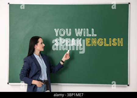 Lehrer, der auf Text zeigt, sprechen Sie Englisch auf grüner Tafel. Sprachkurs Stockfoto