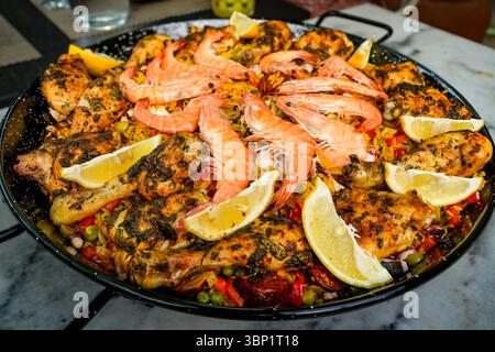 Spanisches Nationalgericht Paella. Paella wird typischerweise mit Reis, verschiedenen Fleisch- oder Fischsorten (wie hier mit Huhn und Garnelen), Gemüse und zubereitet Stockfoto