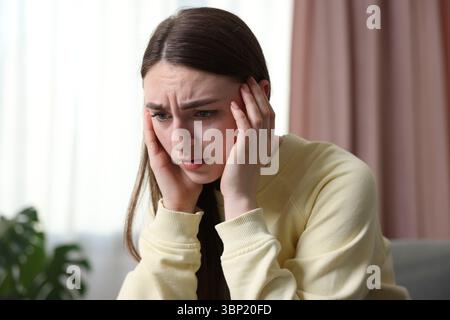 Verängstigte Frau, die zu Hause an Paranoia leidet Stockfoto