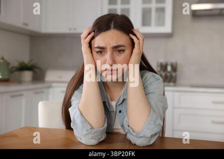 Frau mit Paranoia am Tisch in der Küche Stockfoto