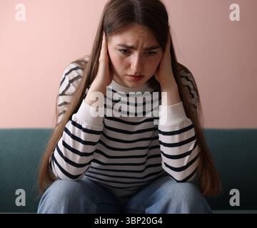 Frau, die zu Hause auf dem Sofa unter Paranoia leidet Stockfoto
