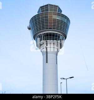 Ein hoher, weißer Flugsicherungsturm mit einem verglasten Oberteil steht vor einem hellblauen Himmel. Stockfoto