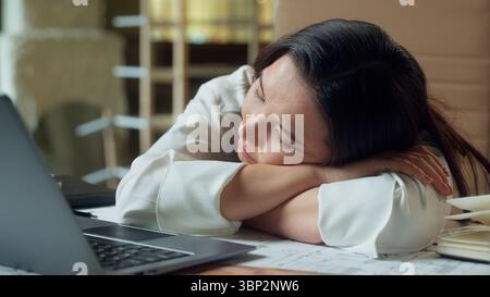 Müde asiatische Geschäftsfrau Geschäftsfrau schlafend auf Bürotisch erschöpft schläfriges Nickerchen Mädchen Chinesisch Koreanisch gelangweilte Frau schlafend auf dem Schreibtisch Stockfoto