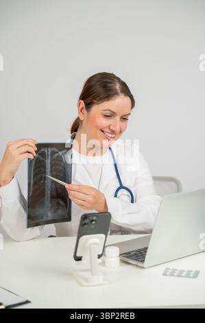 Telemedizin. Kaukasische Ärztin kommuniziert mit dem Patienten auf dem Laptop und zeigt Röntgenaufnahmen der Lunge. Stockfoto