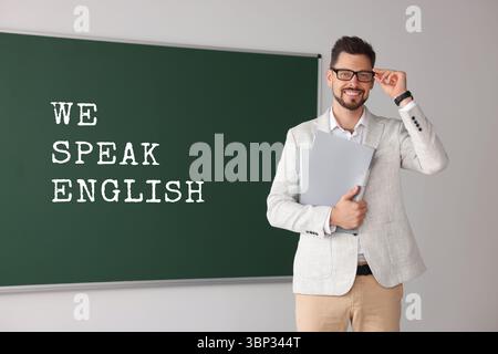 Lehrer in der Nähe der grünen Tafel mit Text Wir sprechen Englisch. Sprachkurs Stockfoto