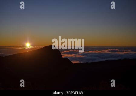 Ein ruhiger Sonnenuntergang mit einem Berg in Silhouette vor einem ruhigen Himmel, La Reunion, Frankreich, Afrika Stockfoto