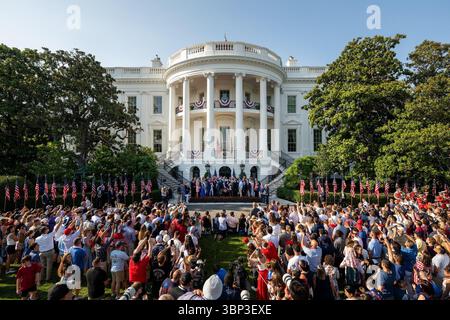Eine große Menschenmenge versammelt sich vor dem Weißen Haus, das mit patriotischen roten, weißen und blauen Fahnen und einer Ausstellung amerikanischer Fahnen geschmückt ist. Zuschauer machen Fotos und beobachten eine Live-Zeremonie, die auf einer zentralen Bühne am Fuß des berühmten nördlichen Portico stattfindet. Die Szene fängt den Geist einer nationalen Feier ein, mit festlicher Einrichtung und einer lebhaften Atmosphäre, die Veranstaltungen zum Unabhängigkeitstag hervorhebt. Washington, D.C. | 4. Juli 2025 | Bild mit freundlicher Genehmigung des Weißen Hauses. Stockfoto
