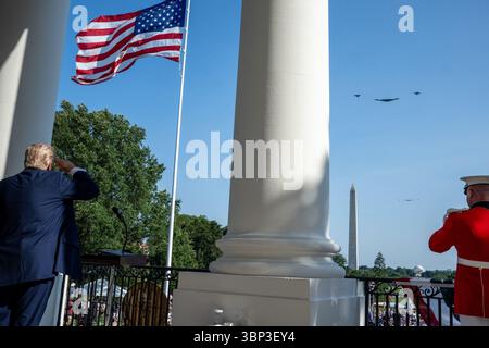 Präsident Donald Trump steht neben einem Militärbeamten in roter Uniform auf einem Balkon des Weißen Hauses, beide begrüssen, während eine Flugzeugformation über dem Dach fliegt. Die amerikanische Flagge erhebt sich stolz vom vorderen Fahnenmast, während das Washington Monument in der Ferne aufragt. Die Szene fängt einen formellen Moment der Hommage während der Unterzeichnungsfeier für die „One Big Beautiful Bill“ ein. Washington, D.C. | 4. Juli 2025 | Bild mit freundlicher Genehmigung des Weißen Hauses. Stockfoto