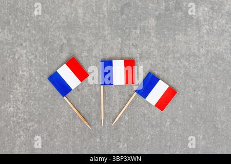 Drei französische Miniflaggen auf grauem Hintergrund Stockfoto