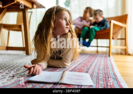 Mädchen mit blonden Haaren, das während des Studiums zu Hause nachdenkt Stockfoto